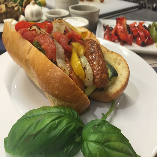 A plated Premio sausage hero with peppers and a basil leaf garnish