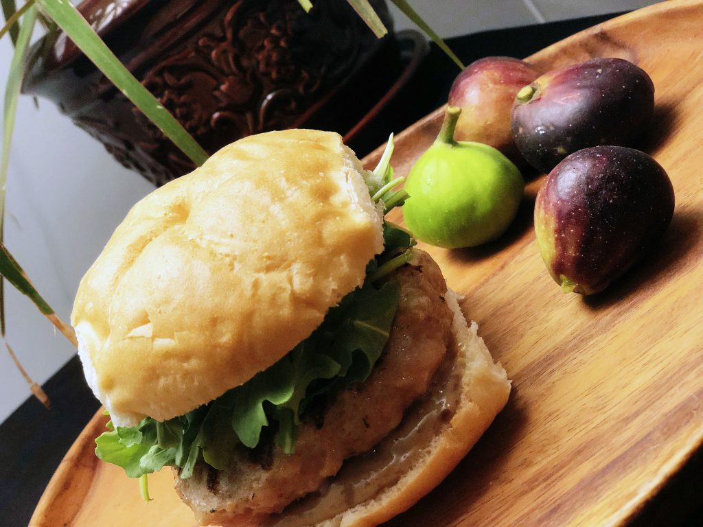A chicken sausage burger topped with greens and a zesty fig mustard