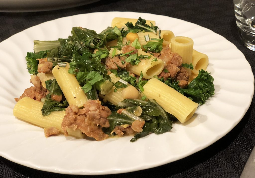 A plate of pasta topped with chopped greens, Premio sausage crumbles and chickpeas