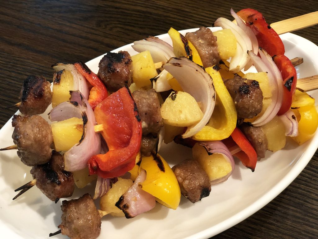 A plate of pineapple, onion and quality Premio sausage kebabs