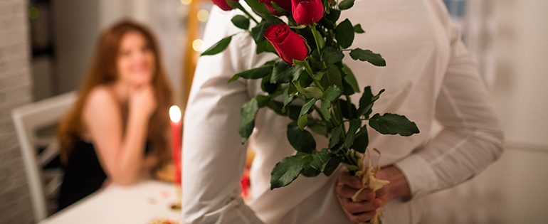 man holding roses behind back for Valentine's Day