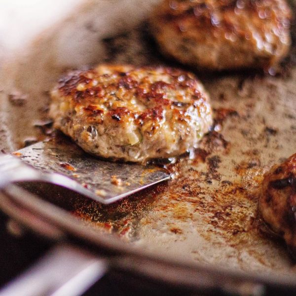 Cooked sausage patties being transferred from the pan