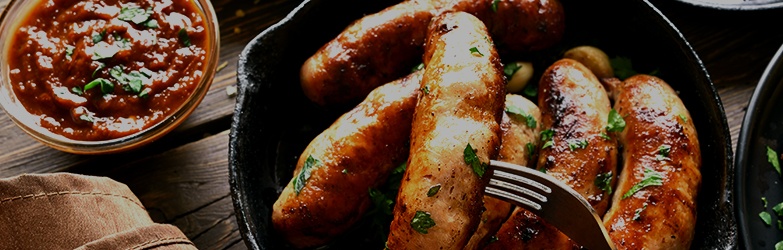 Sausage in skillet with a side of dipping sauce
