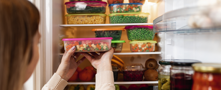 Woman Putting Meal Prep Containers in Fridge