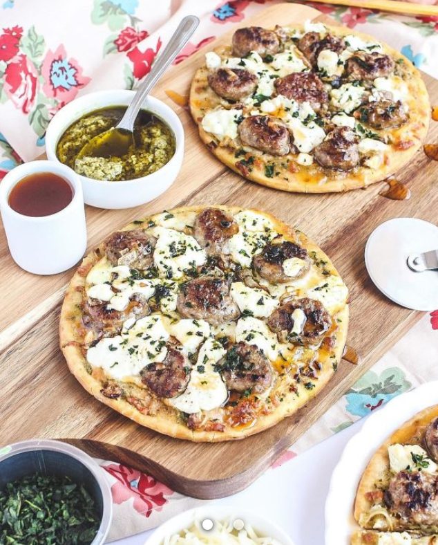Pizza Topped with Pesto, Caramelized Onions, Sausage, Mozzarella, Goat Cheese, Basil and Hot Honey