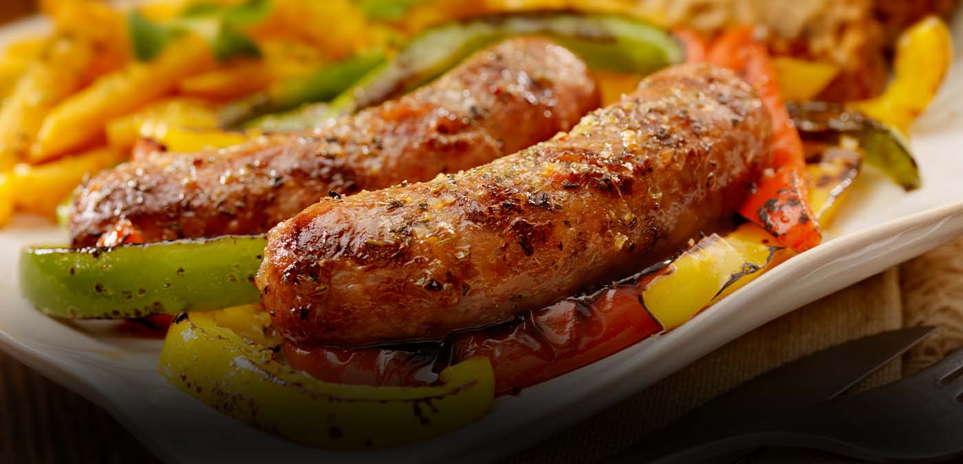 An image of cooked sausage on a bed of multicolored peppers