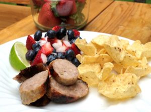 Sliced Premio sausage served with a strawberry, blueberry, and onion salsa and chips
